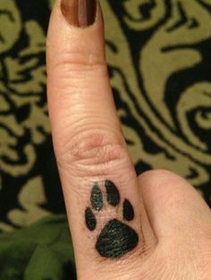 a person's finger with a dog paw tattoo on it