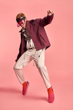 a man in a purple jacket and red shoes is dancing with his arms out to the side