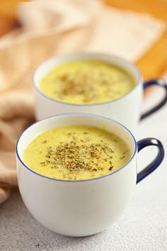 two white cups filled with soup on top of a table