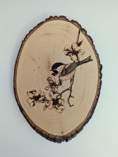 a bird sitting on top of a piece of wood with flowers in the center,