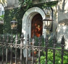 an iron fence is in front of a house with ivy growing on the walls and door