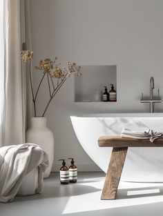 a white bathroom with a wooden table and vases on the floor next to it