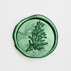 a green wax stamp with a plant on it's side and leaves drawn on the bottom