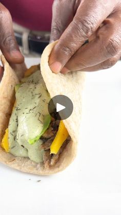 a person is holding a burrito with some sort of sauce on top of it