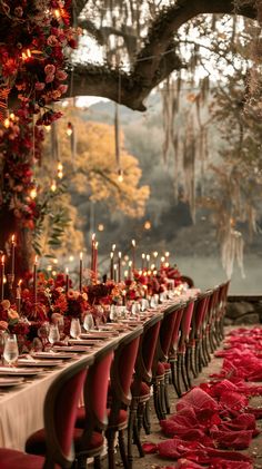 a long table is set with red flowers and candles for a formal dinner or party