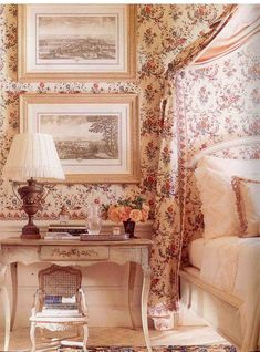 a bedroom with floral wallpaper and paintings on the walls