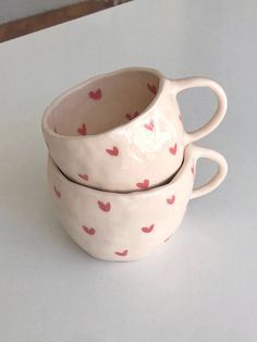 two white cups with hearts on them sitting on a table