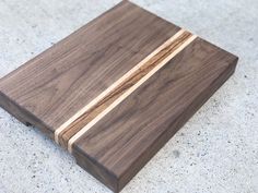 a wooden cutting board sitting on top of a cement floor next to a white wall