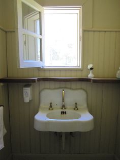 a white sink sitting under a window in a bathroom