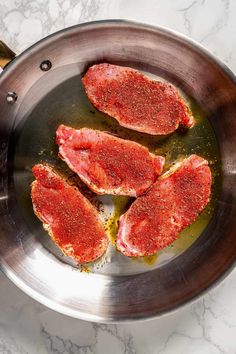 three pieces of meat in a pan with seasoning