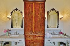 a bathroom with two sinks and a large wooden cabinet in the middle of the room