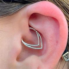 a woman's ear is shown with two small silver hoops