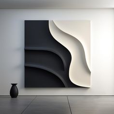 an abstract black and white painting hangs on the wall next to a vase in front of it