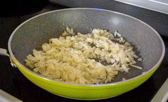 onions are being cooked in a green pan on the stove top, ready to cook