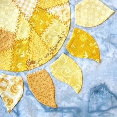 a yellow and white patchwork piece with leaves on it's side, sitting on a blue background