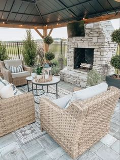 an outdoor living area with wicker furniture and a stone fire place in the center