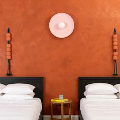 two twin beds in a room with orange walls and black headboards on either side