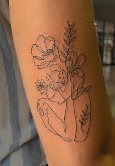 a woman's arm with flowers and leaves on it