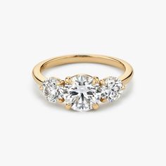 three stone engagement ring in yellow gold with diamonds on the sides and an oval diamond center