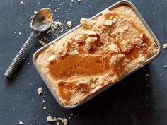 an ice cream dish with nuts and caramel sauce in it next to a spoon