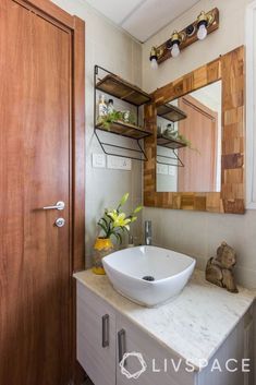 a bathroom sink sitting under a mirror on top of a counter next to a wooden door