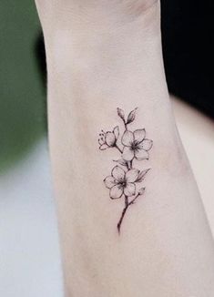 a small flower tattoo on the ankle is shown in black and grey ink, with white flowers