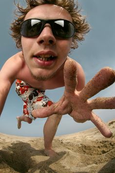 a man with sunglasses on his head is in the sand and has one hand out