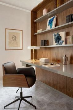 a chair sits in front of a desk with books on it and shelves above the desk