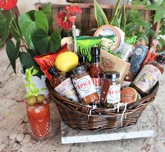 a wicker basket filled with condiments and drinks on a table next to potted plants