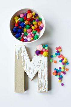 the letters m and m are decorated with pom - poms in different colors