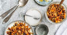 two bowls filled with granola next to spoons