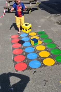 a little boy standing on top of a sidewalk next to a colorful block and circle pattern