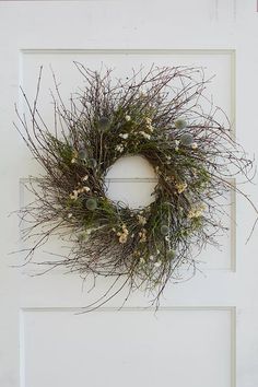 a white door with a wreath hanging on it's side and flowers in the middle