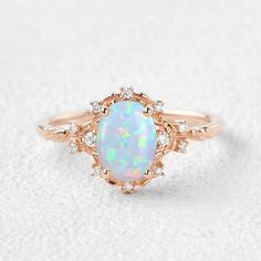 a white opal and diamond ring on a white surface with an oval shaped setting