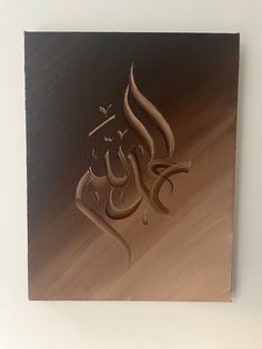 an arabic calligraphy is displayed on a white wall with a black frame and brown background