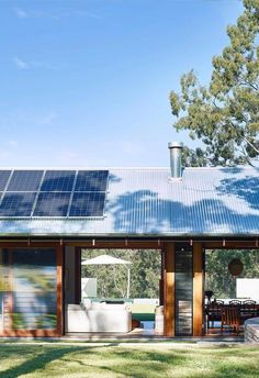 a house with solar panels on the roof and patio furniture set up outside in front of it