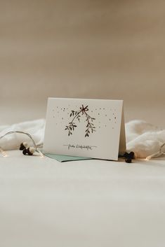 a white card with a black and red flower on it sitting on top of a bed