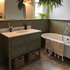 a bathroom with a sink, bathtub and plants hanging from the ceiling above it