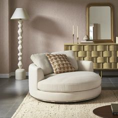 a living room with a white chair and a gold mirror on the wall next to it