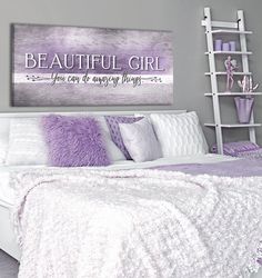 a white bed topped with purple pillows and blankets