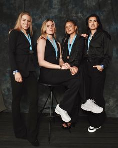 four women in black suits posing for a photo