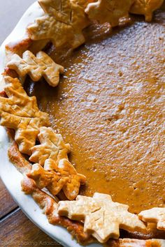 a pumpkin pie on a white plate topped with star shaped cut out cookies and leaves