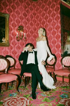 a bride and groom pose for a photo in an ornately decorated room with pink chairs