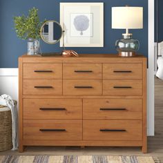 a wooden dresser sitting next to a bed with blue walls and pictures on the wall