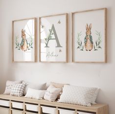 three framed pictures hang on the wall above a bench with pillows and baskets underneath them