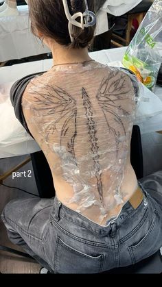 the back of a woman's body with tattoos on it