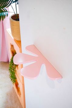 a potted plant sitting on top of a wooden shelf next to a white wall