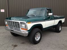 a green and white pick up truck parked in front of a building