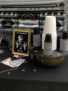 a table topped with lots of black and white paper cups next to a framed photo