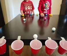 two young boys playing with plastic cups and balls on a table in the living room